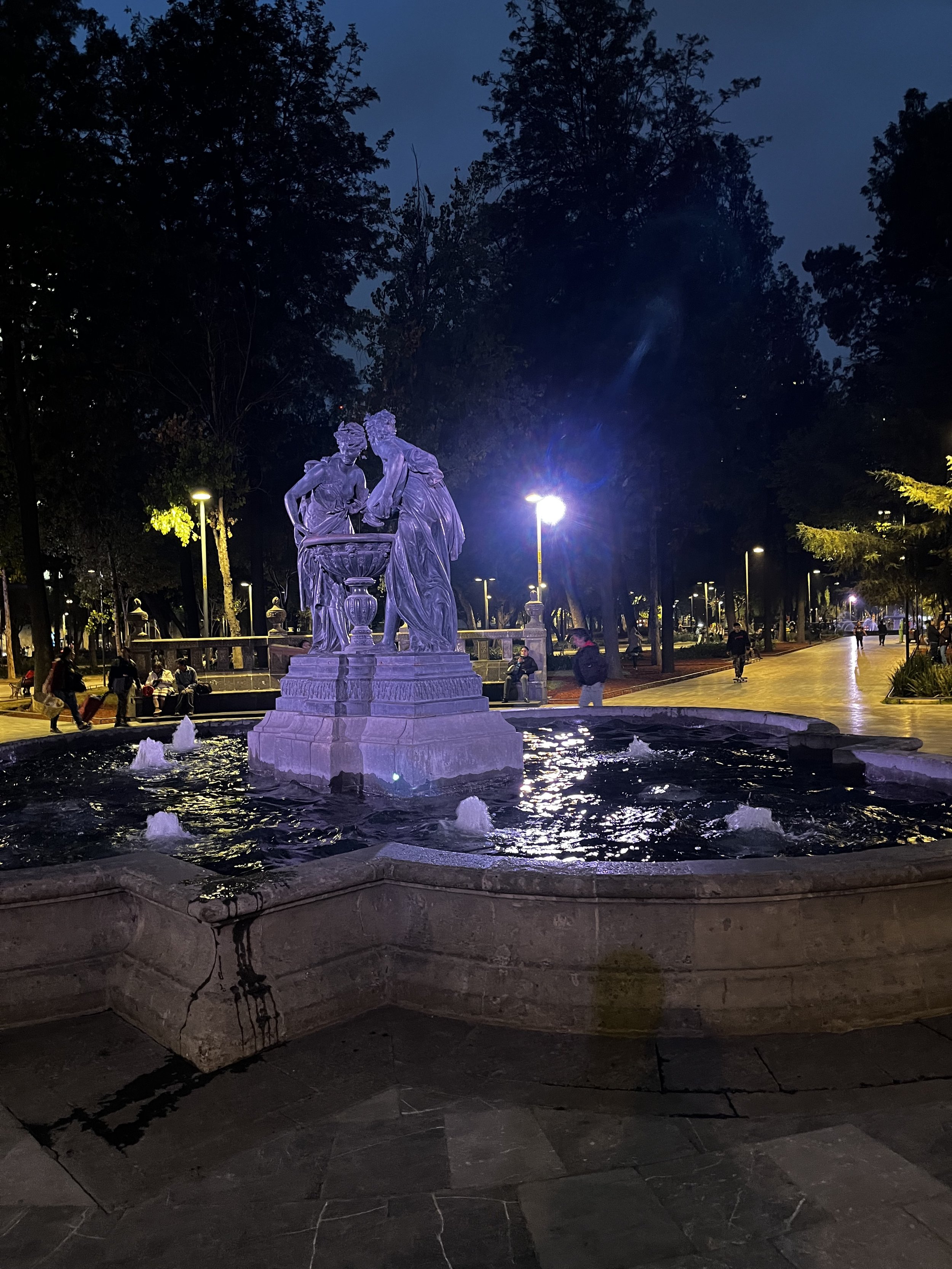 Purple lights tint the gorgeous marble statue in a fountain in Parque Alameda.