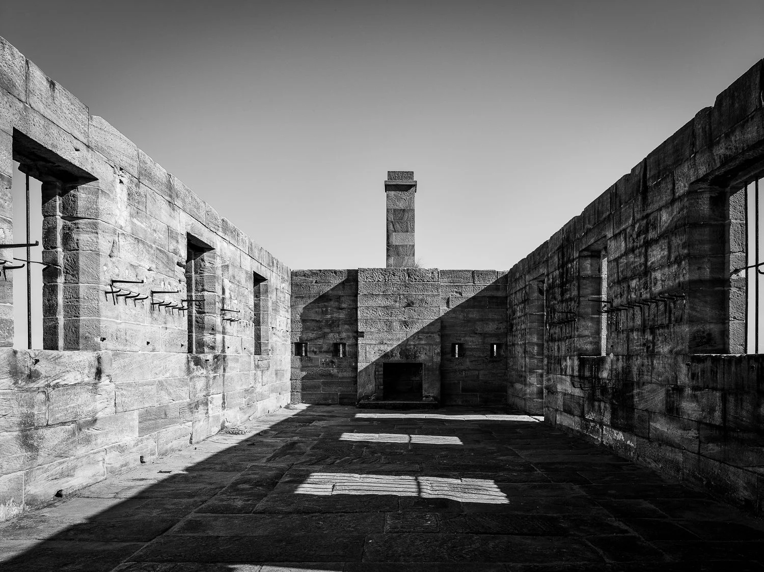 Black and white photo of the interior of the Memorial to the Murdered Jews of Europe in Berlin, showing stone slabs and shadows.