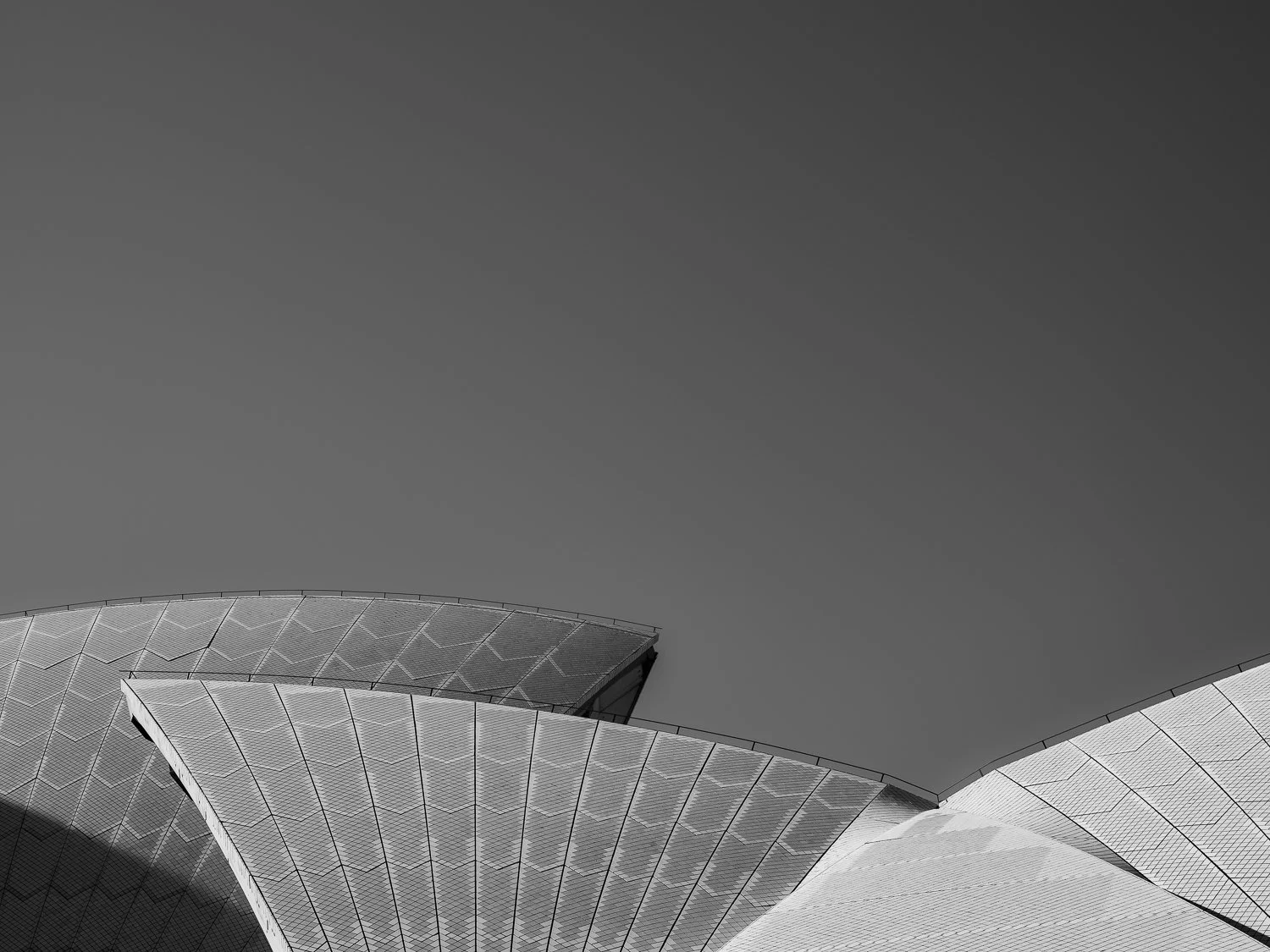 Close-up of the Sydney Opera House with a cloudy sky in the background.