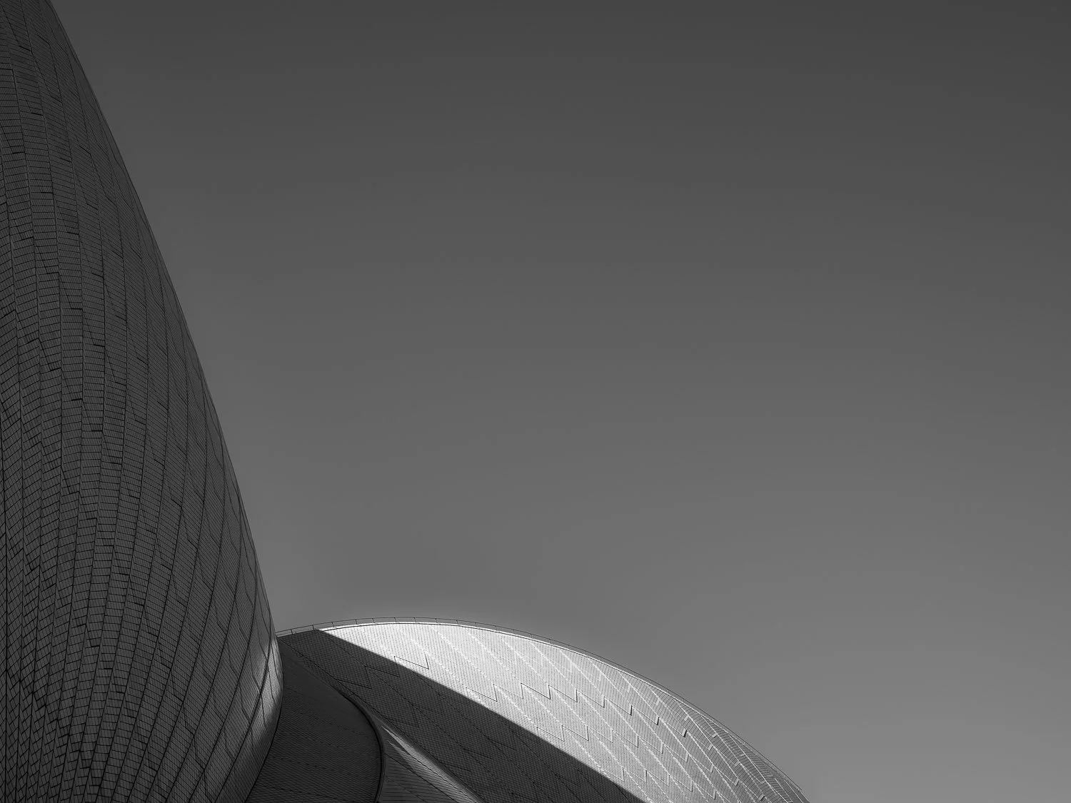 Close-up view of modern architectural buildings with curved surfaces and reflective glass, against a clear sky.