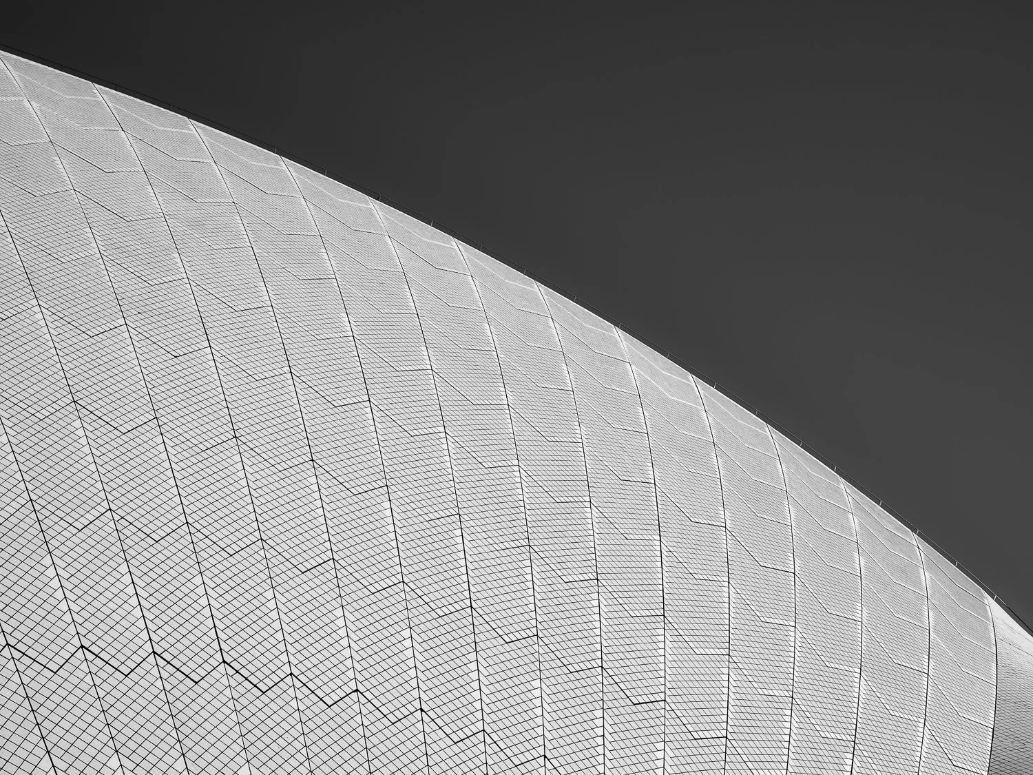 Close-up of a large, curved geometric metallic structure with a grid pattern, set against a dark sky.