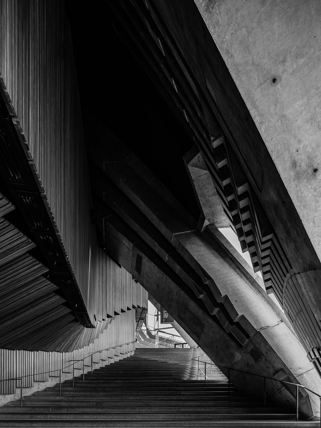 Black and white photo of modern architectural structure with stairs, curved walls, and geometric design elements.