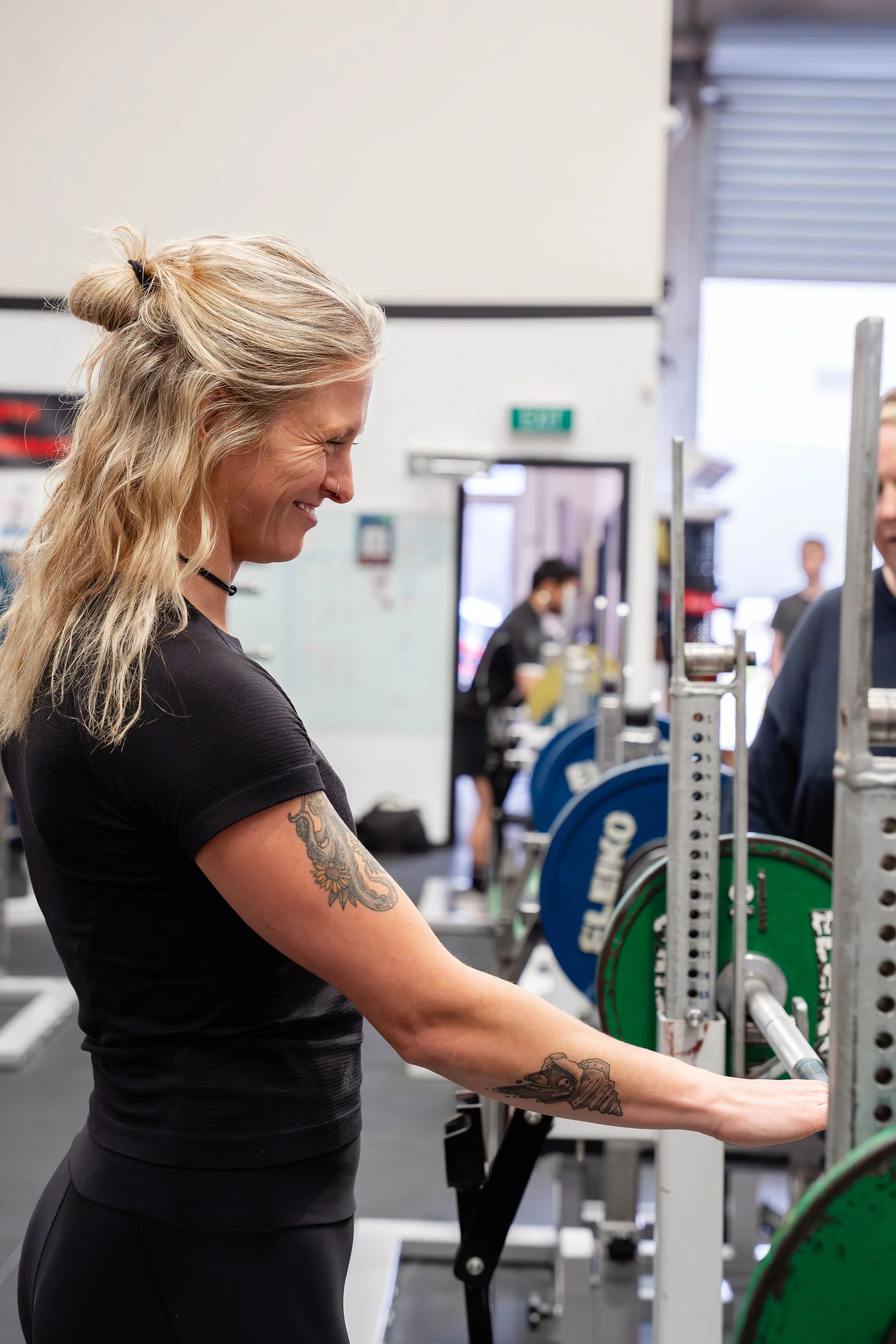 Coach Billie smiles at a lifter who is out of frame after a set of bench press