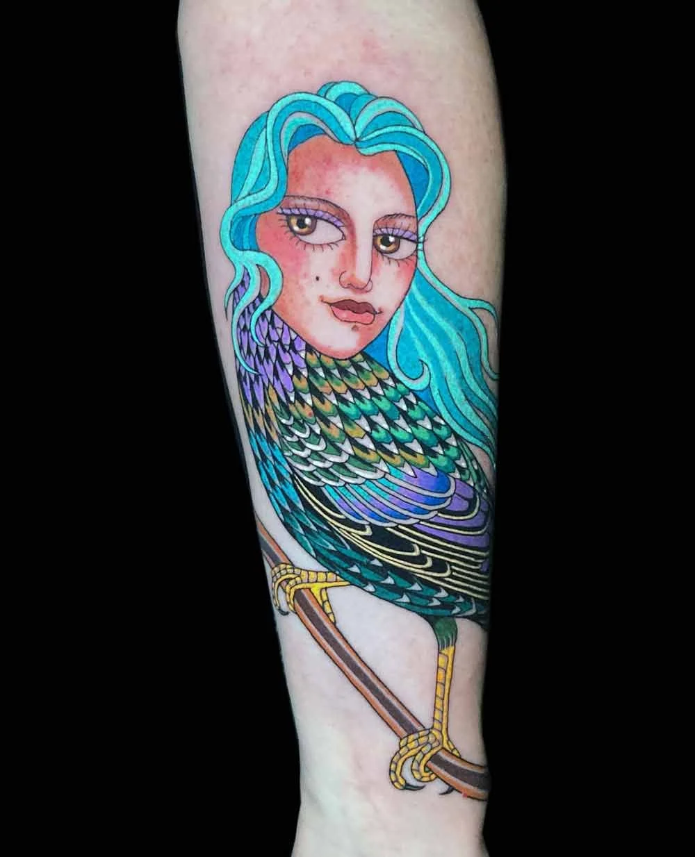 Bright bold delicate neotraditional realistic style colourful tattoo of a harpy starling bird on a womans forearm 