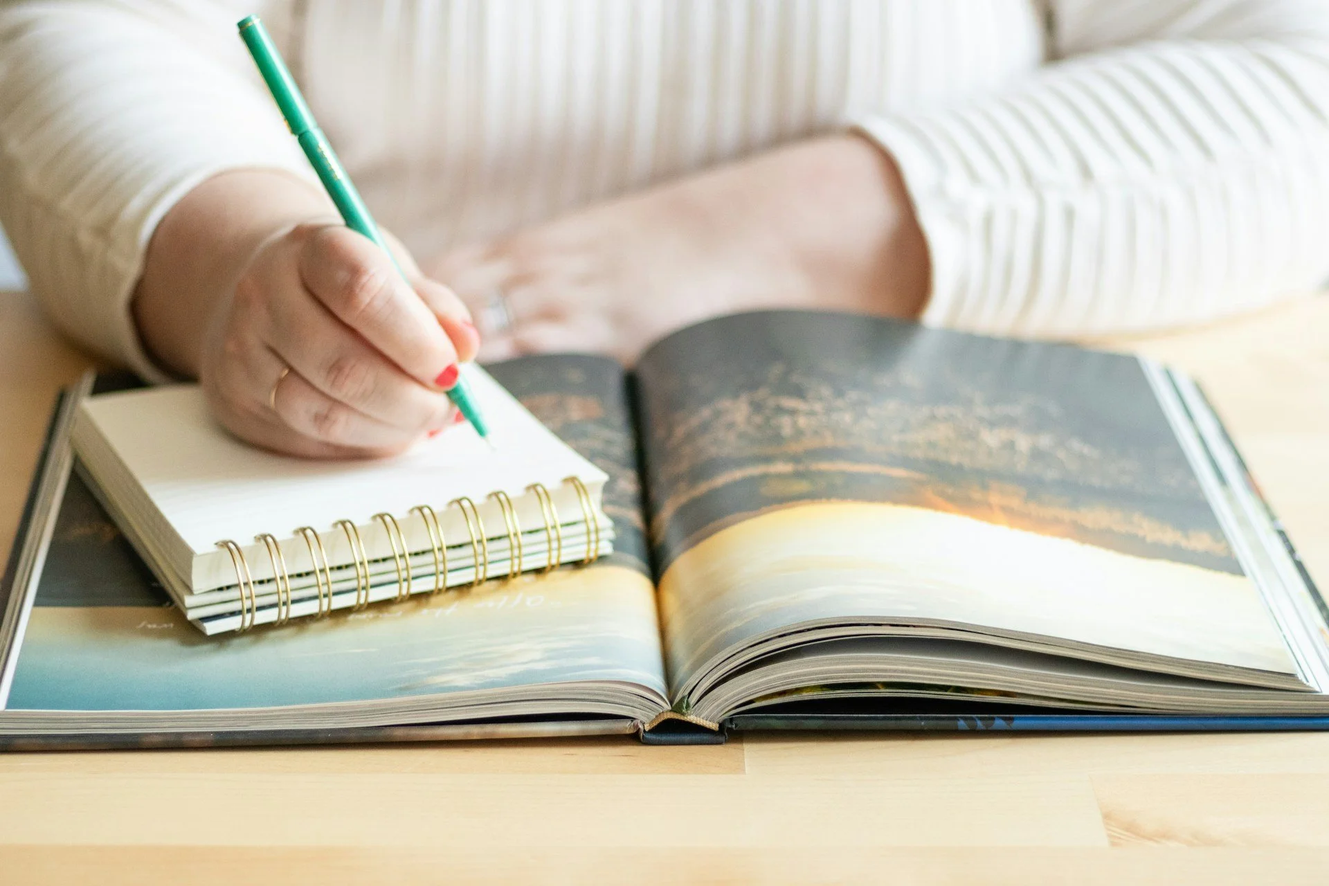 A person writing on a book with a green pen