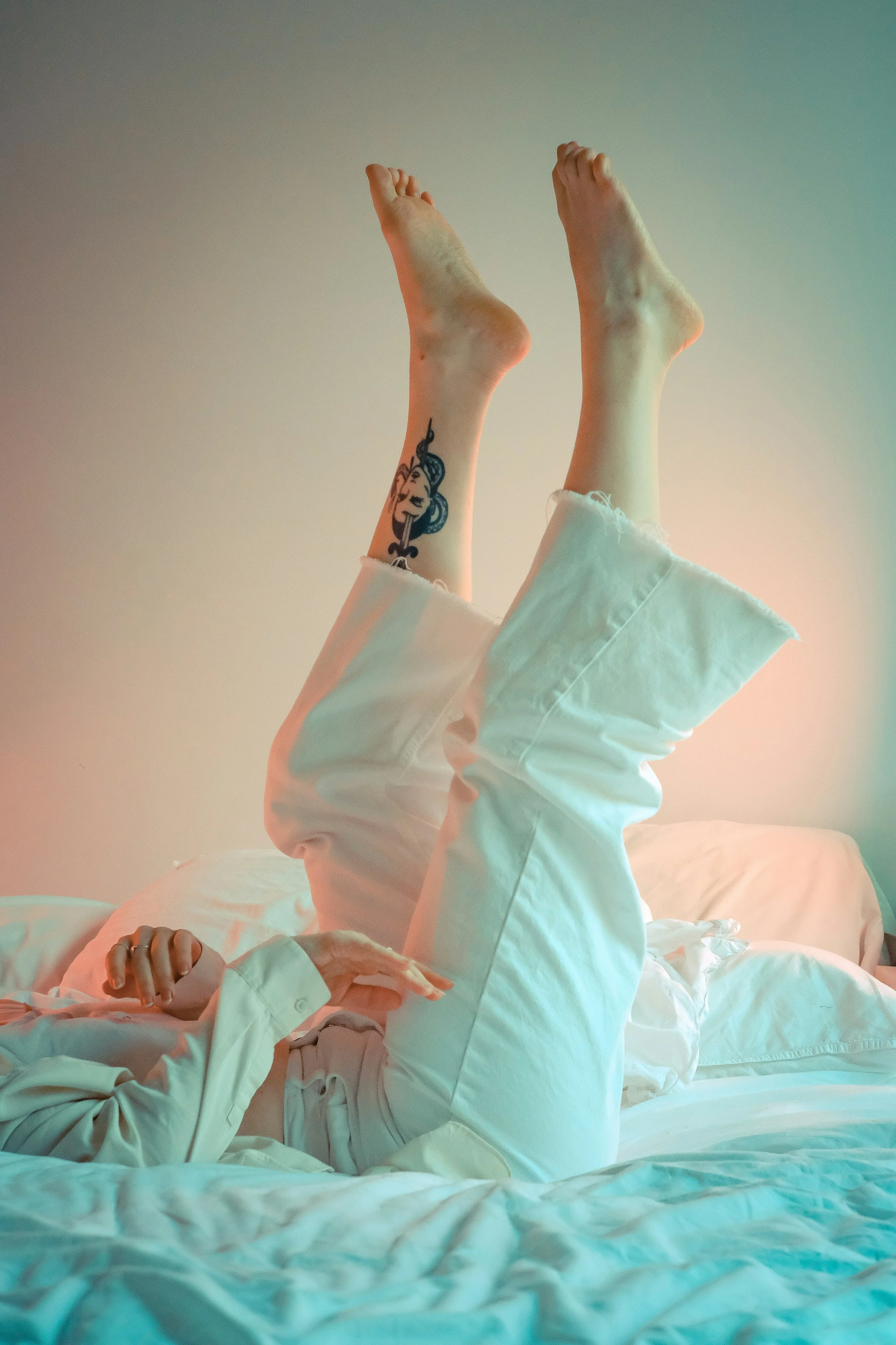 Person with black and red tattoo on right leg laying in bed comfortably