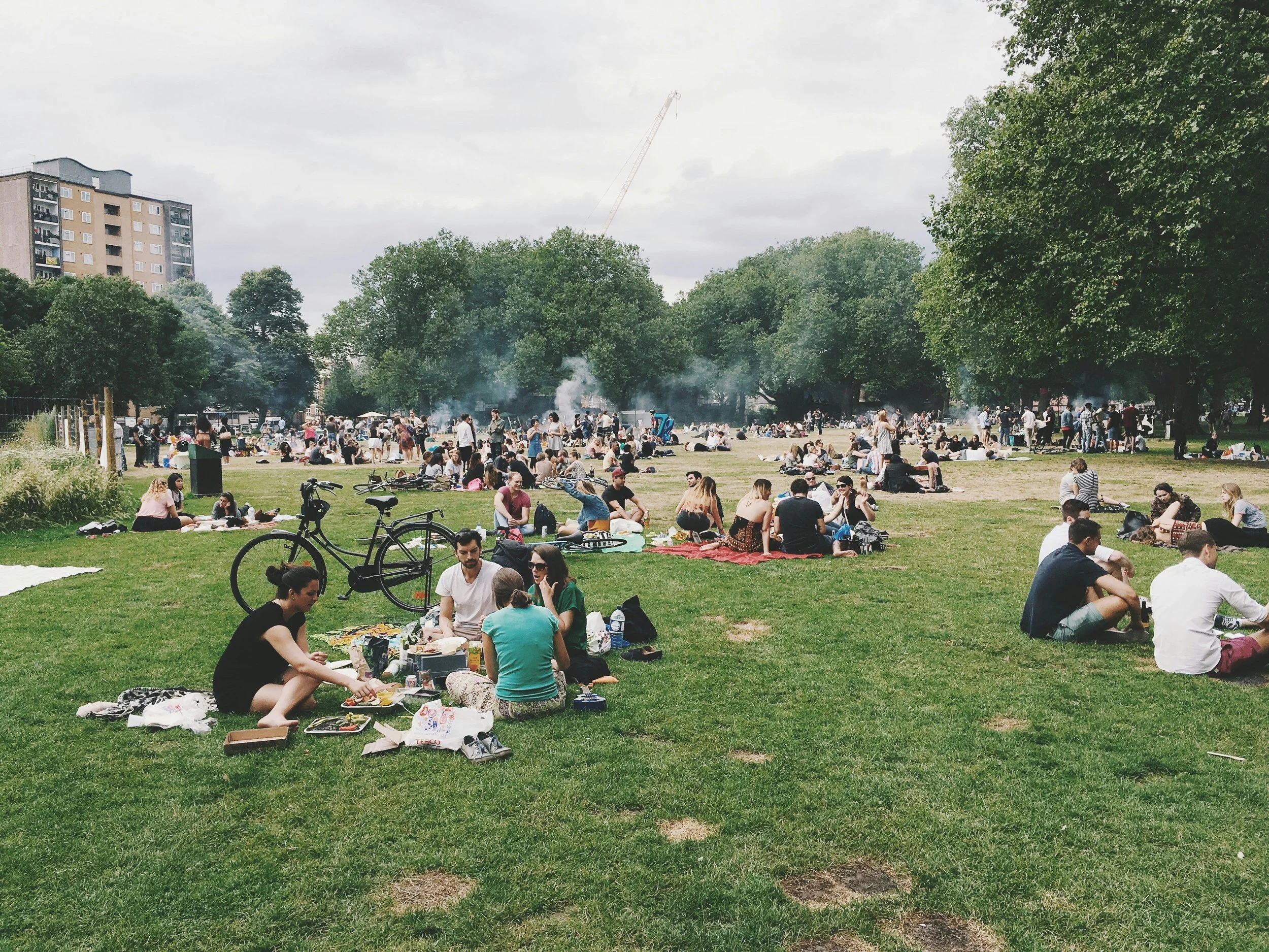 Group of people gathering on field, eating and chatting