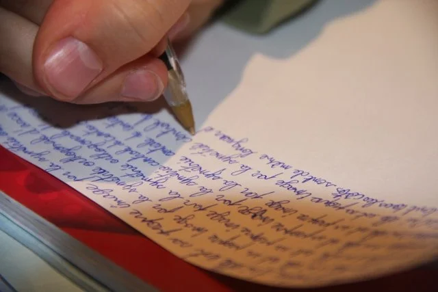 A person writing on a piece of paper with a pen.