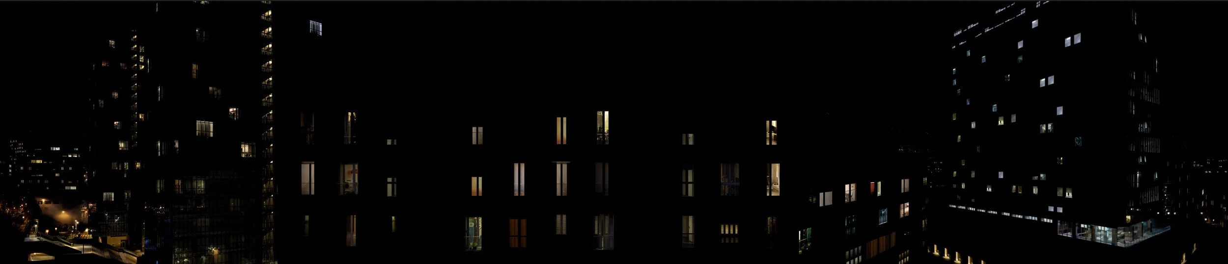 Vista nocturna de un edificio con muchas ventanas iluminadas en una ciudad