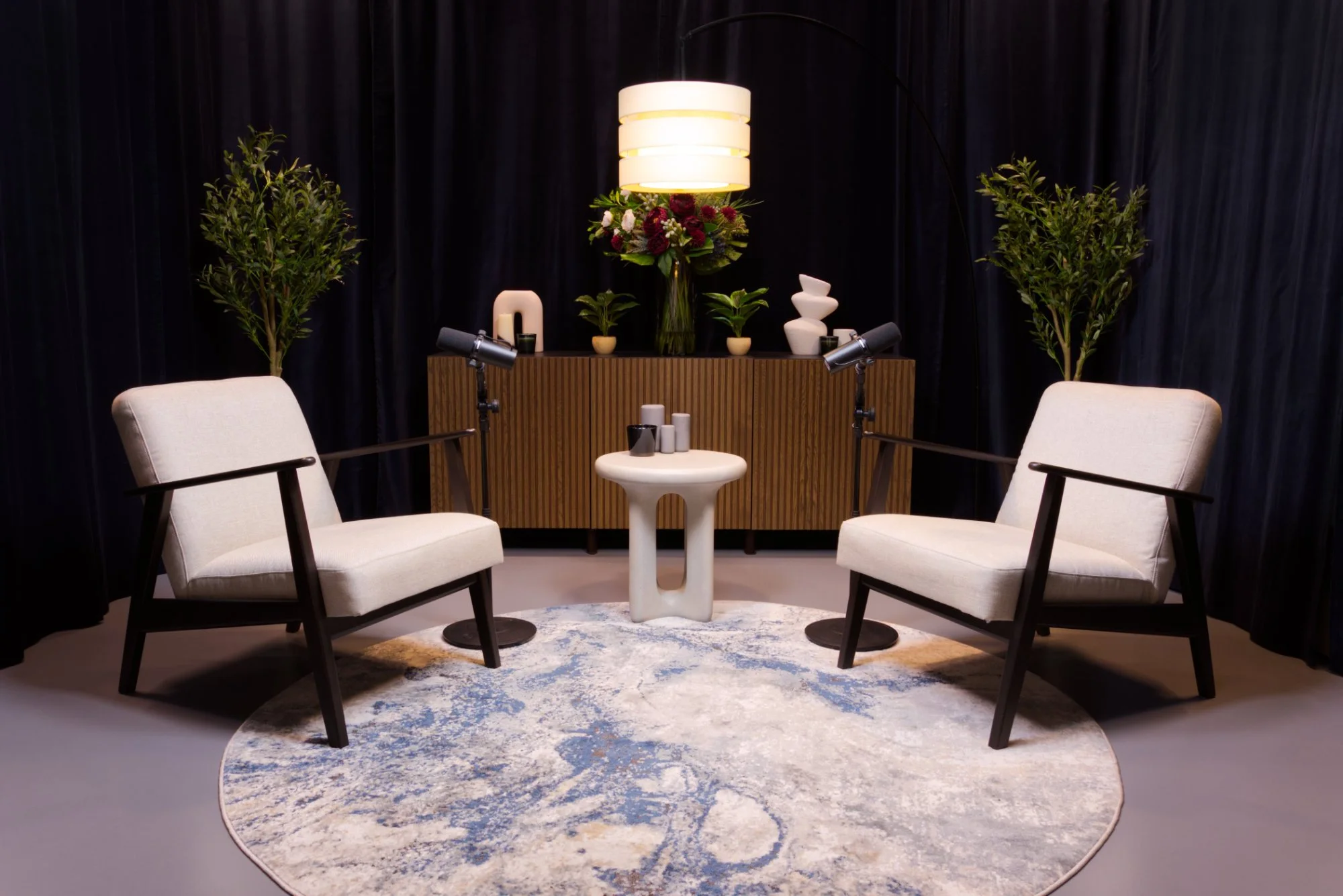 Armchair podcast studio set in London with two professional microphones, cream armchairs and studio lighting.