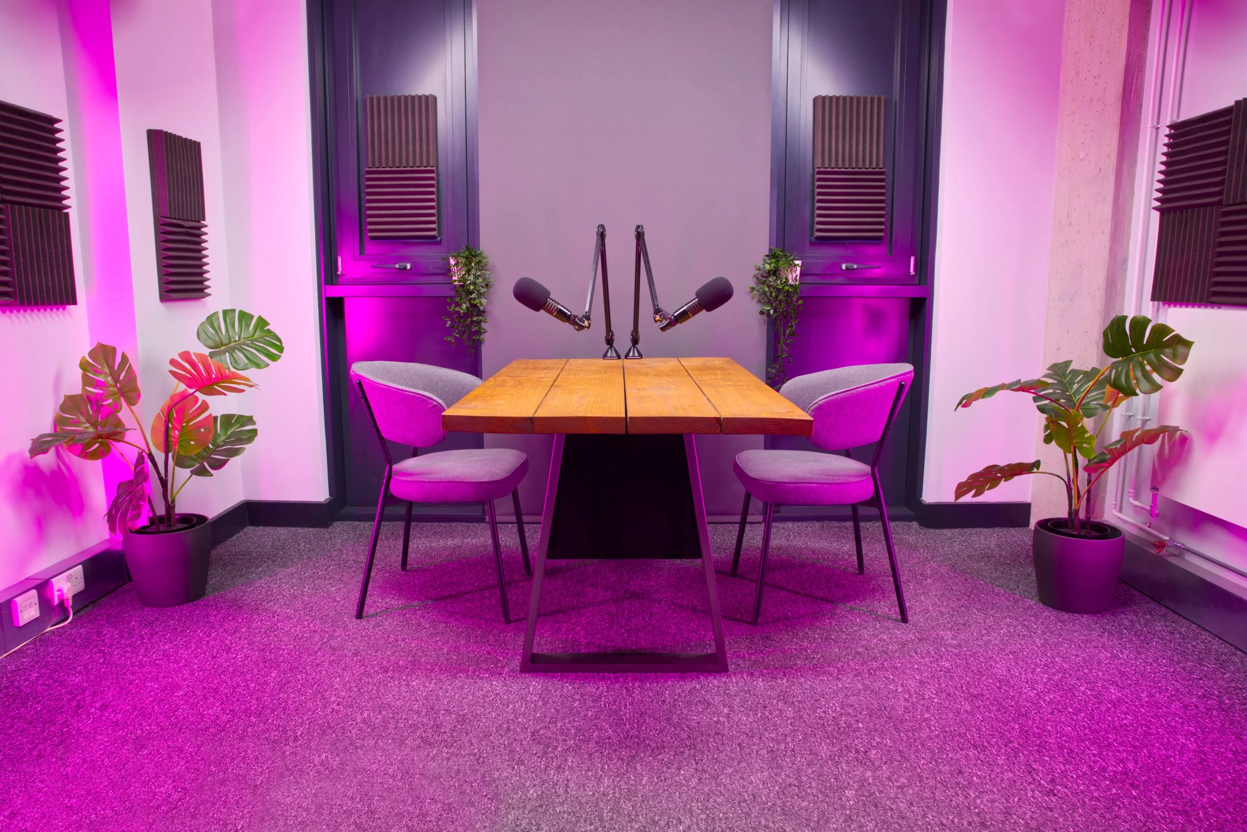 Table podcast set at Podcast Studio Hire in London, with a wooden table, professional microphones, acoustic treatment and studio lighting.