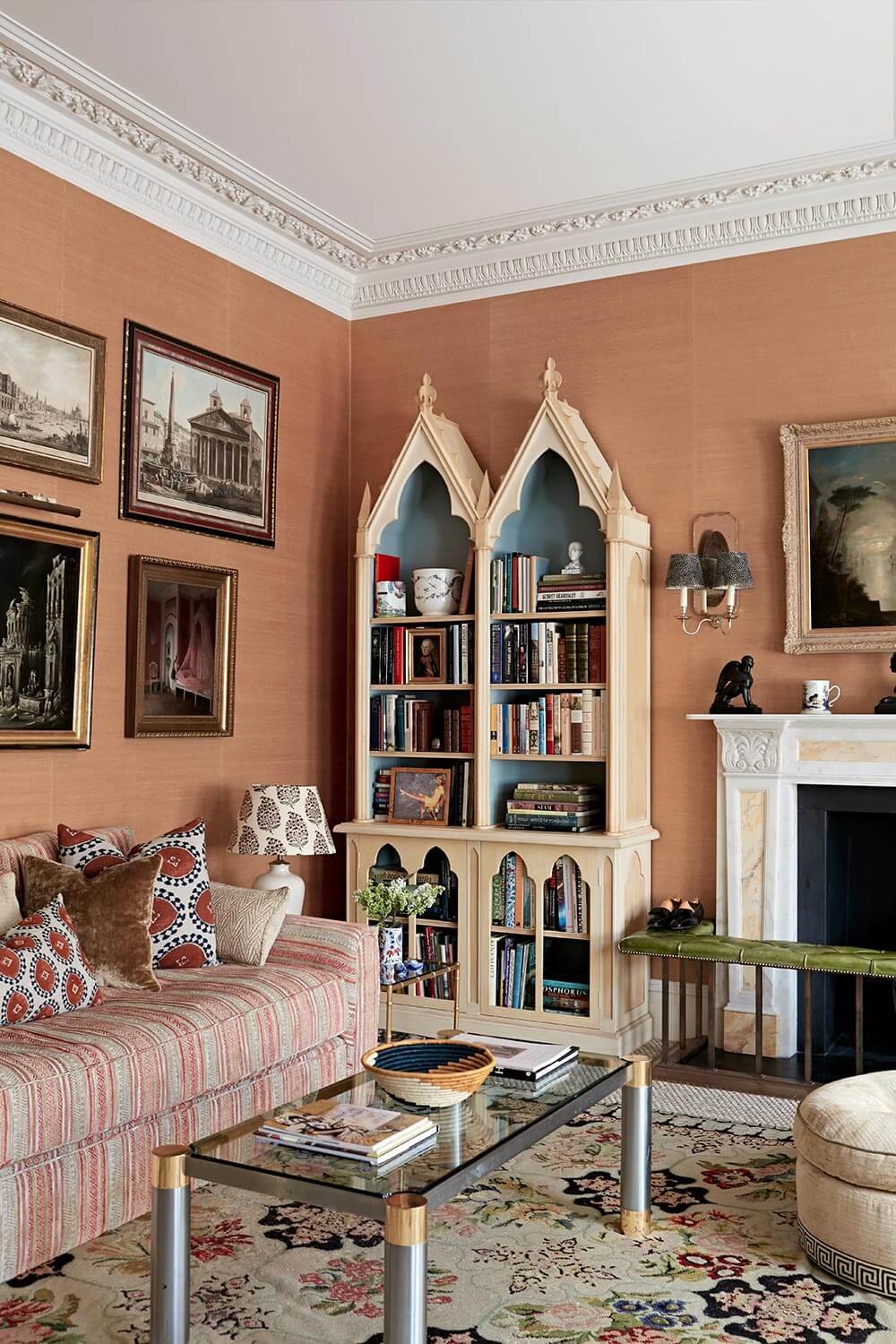 Glass coffee table mixed with sumptuously upholstered sofas, situated by gothic bookcases in a stunning lounge designed by Rab & Co Interior Design-Hampstead