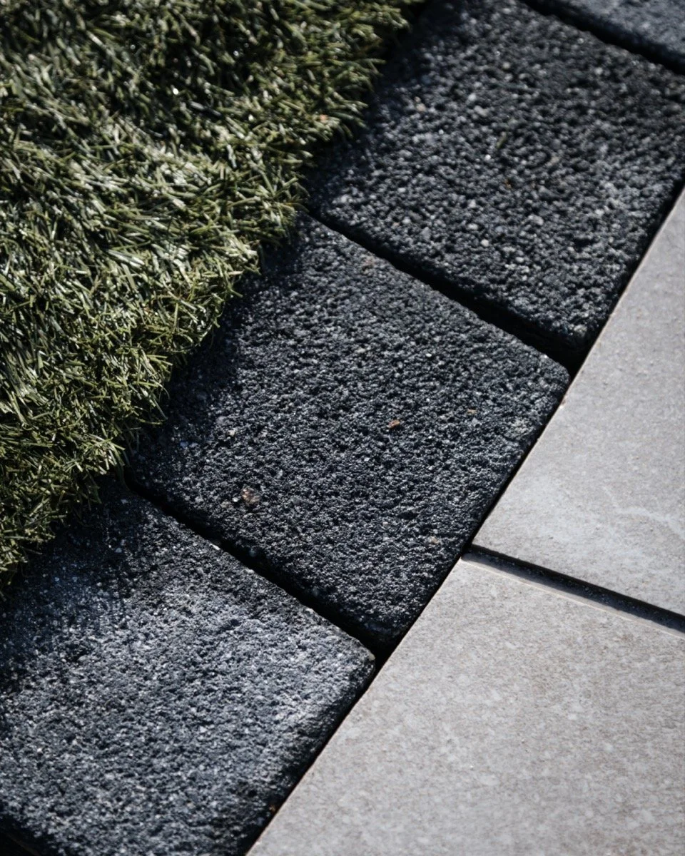 Premium porcelain paving installation with contrasting edging, decorative stone and structured garden planting.