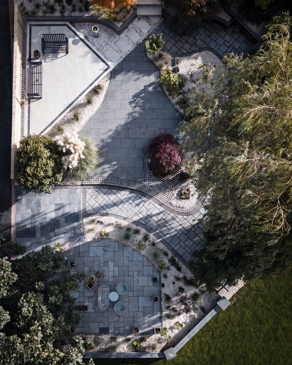 Beautifully landscaped garden with precision-laid paving, decorative stone and established trees.
