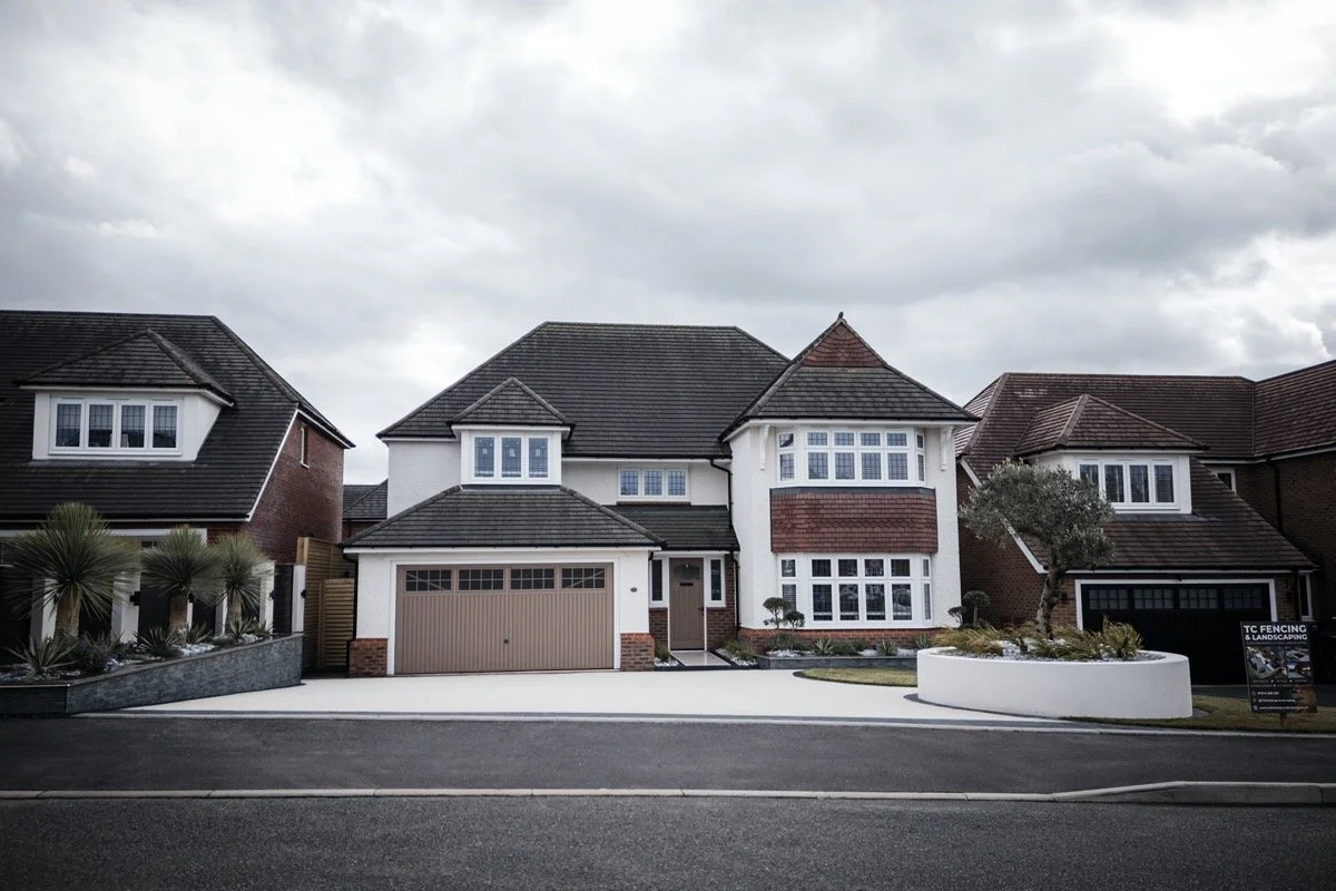 view of contemporary garden landscaping with porcelain paving, curved lawn and outdoor seating area.