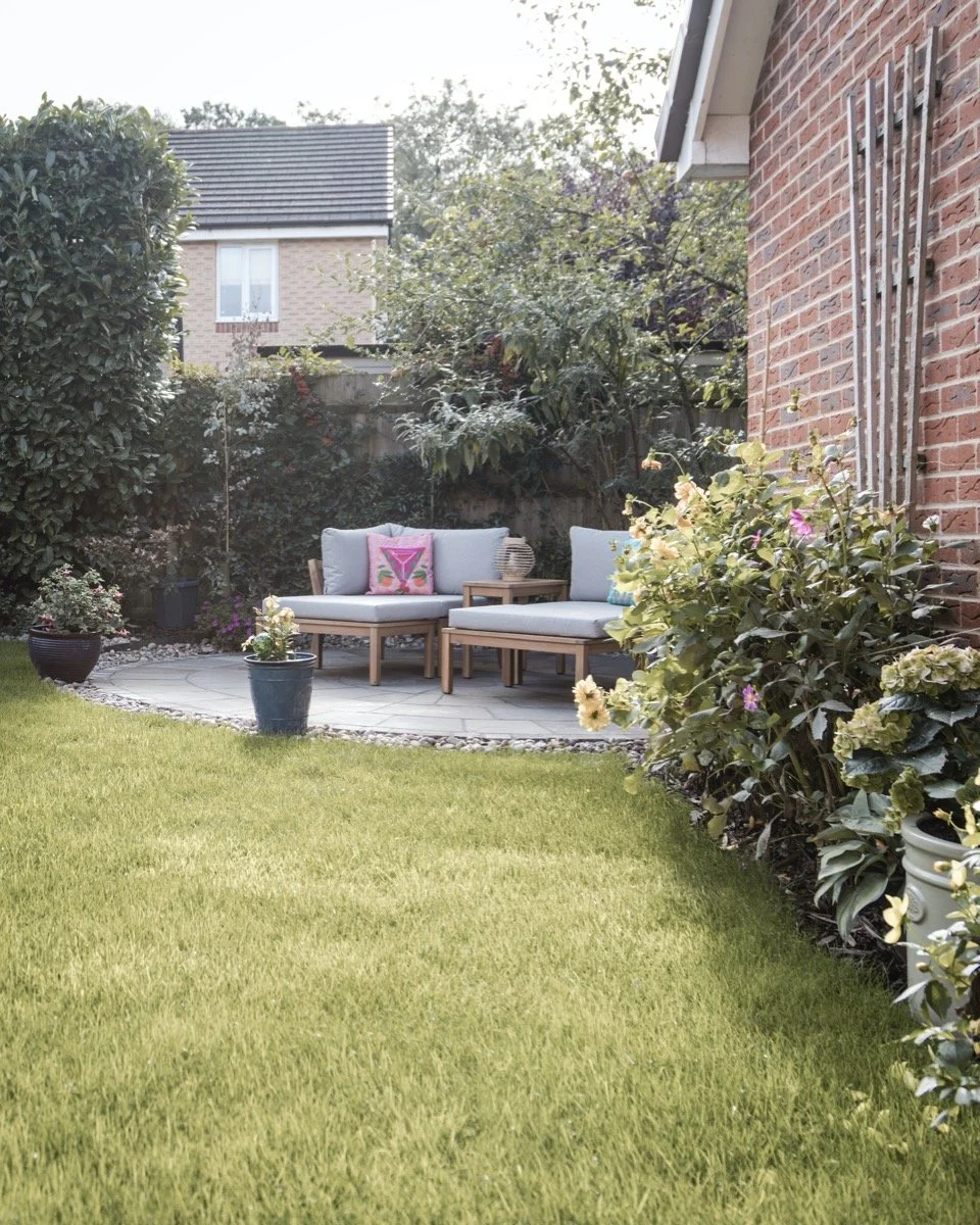 Curved natural stone patio with comfortable garden seating and established planting.