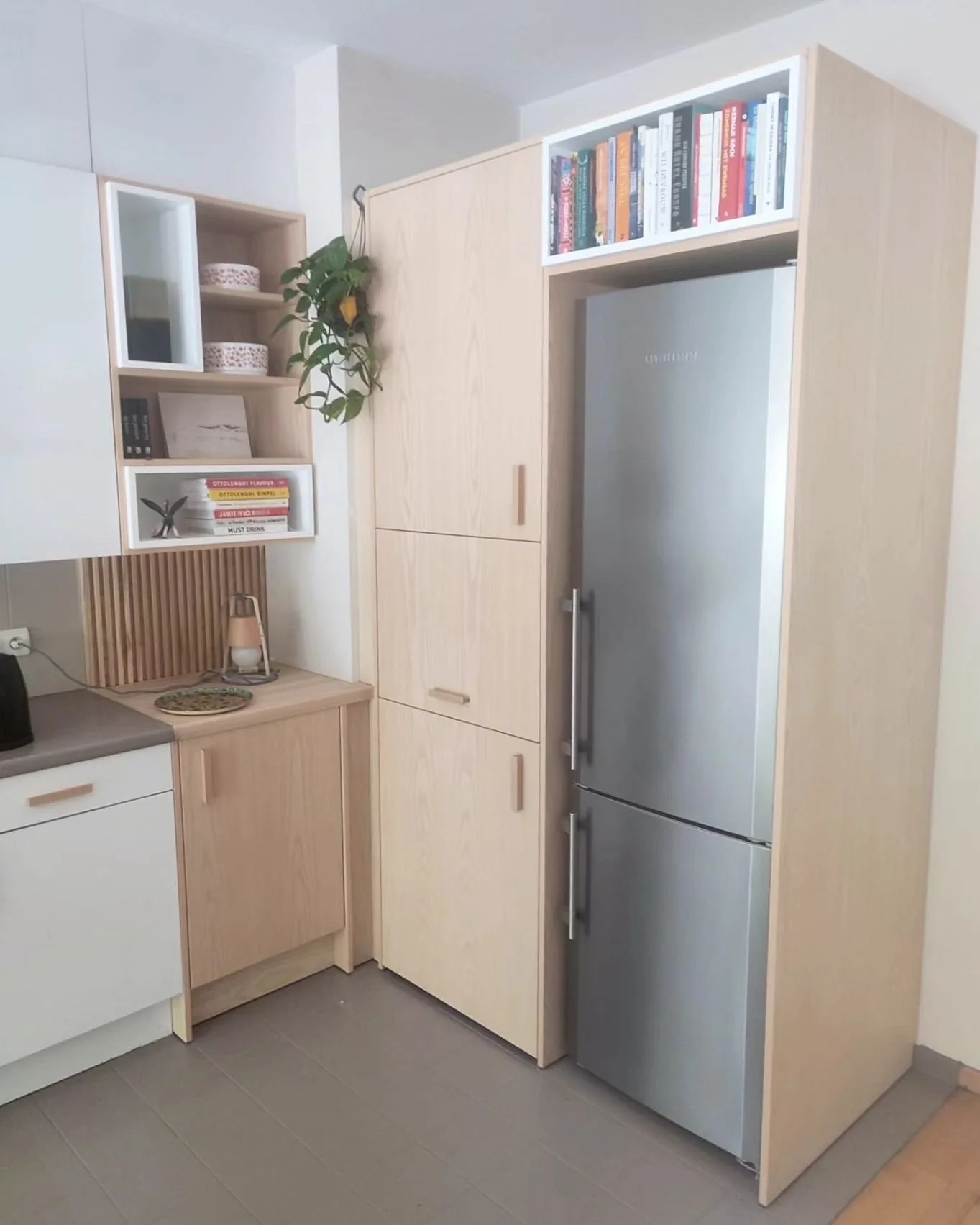 Kitchen extension integrating a washing machine, a stand-alone fridge and a microwave.

Harmonious enlargement of kitchen and hiding household appliances in built-in cabinets.

The counter has been finished with vertical ash wood slats. Several white