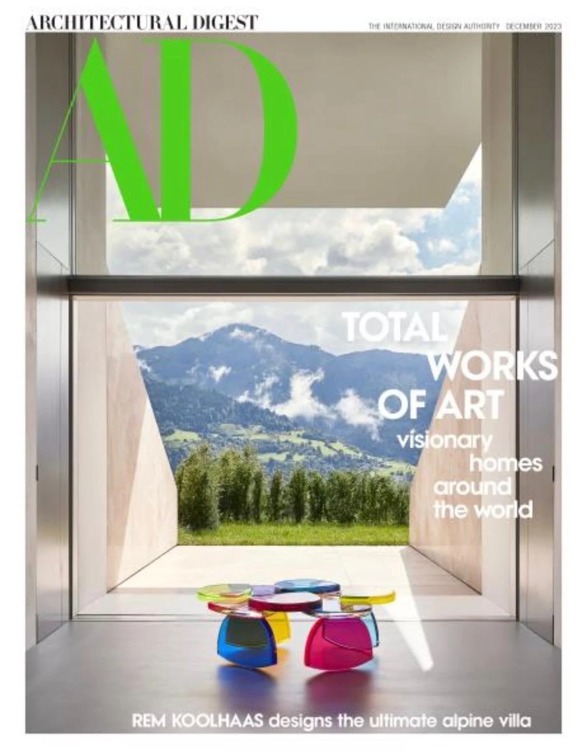 A colorful kitchen with green cabinets, open wooden shelves, and floral wallpaper. The kitchen features a white countertop with stools, a bowl of lemons, a loaf of bread, and a stovetop with a white pot. There are plants and kitchenware on the shelves and a bookcase on the right side.