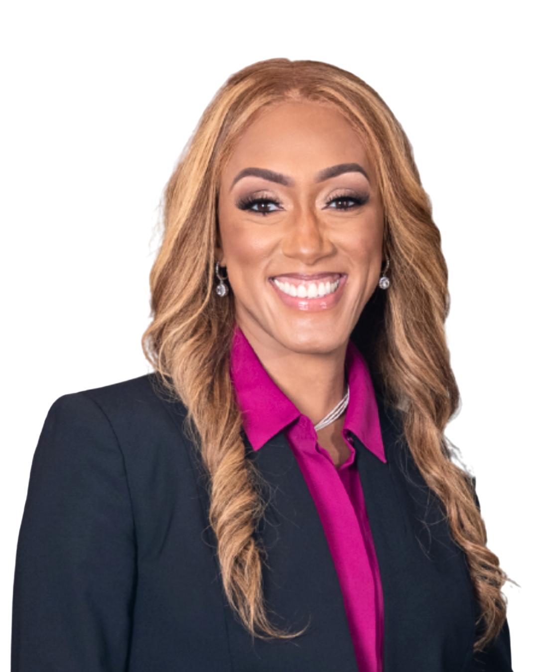 A woman with long, wavy blonde hair, smiling, wearing a black blazer over a pink blouse, earrings, and a necklace.