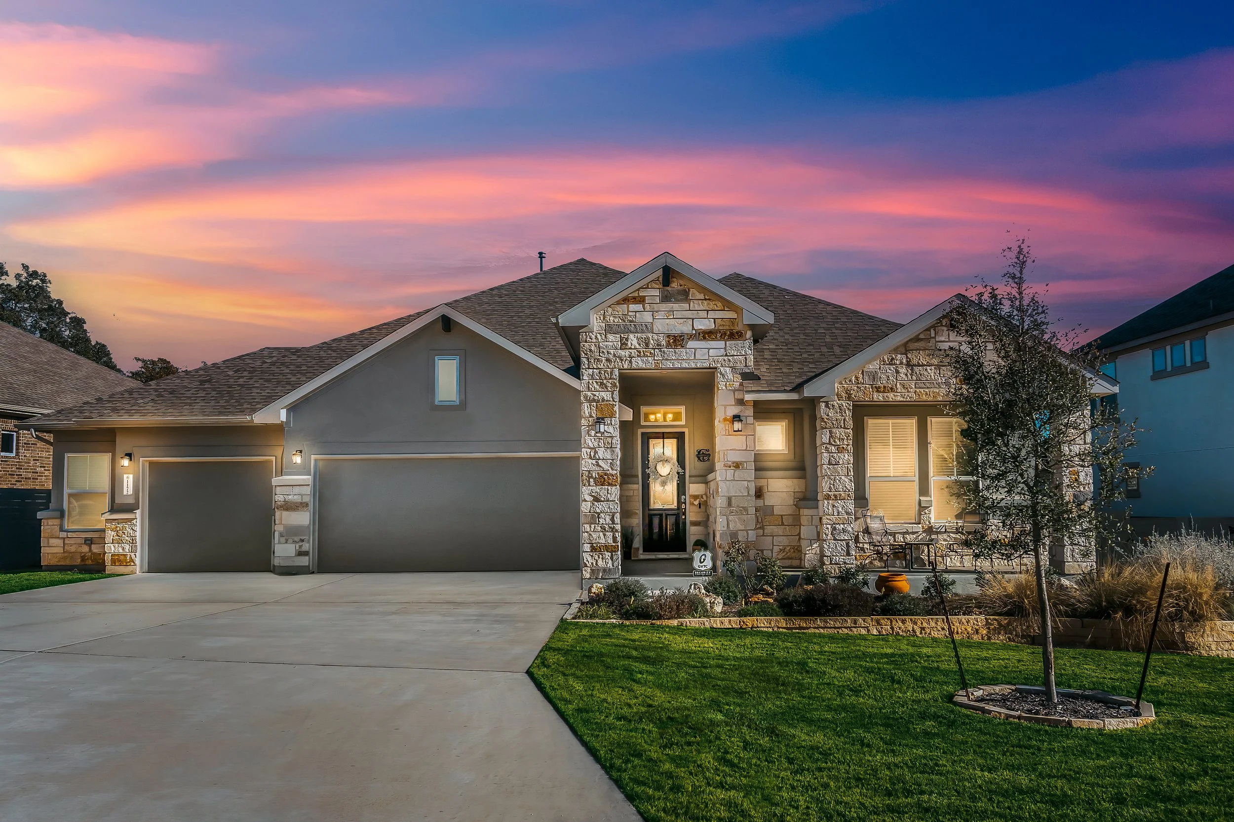 Front yard landscape design with stone veneer home exterior, outdoor lighting, manicured lawn, and entryway landscaping in Delaware by Studio G Outdoor Living