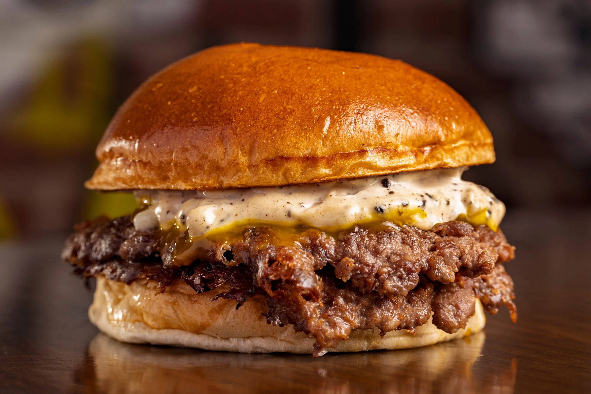 Petey and Ken cooking juicy Cooper Sharp smash burgers on an outdoor grill as part of Recipe Sunday. This backyard cooking scene highlights outdoor living and custom outdoor kitchen experiences by Studio G Interior Spaces & Outdoor Living.