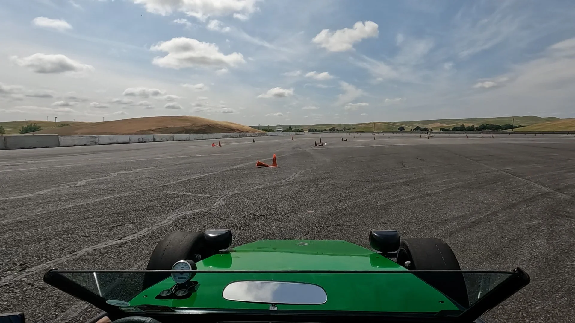 The view from the EV race car on an autocross track showing cones and hills in the background