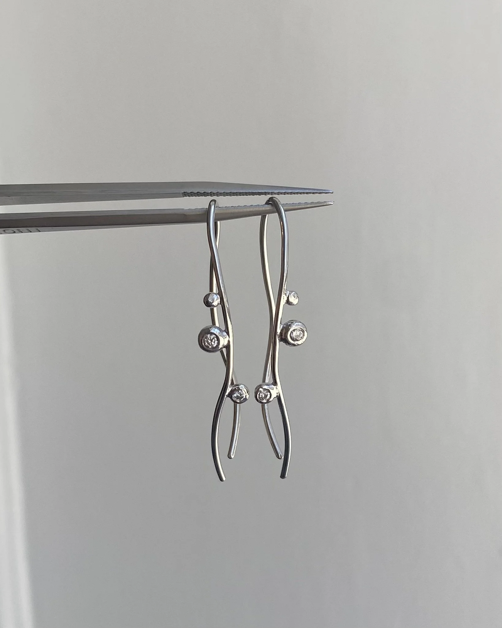 Lange hvidgulds ørebøjler med små dots og diamanter