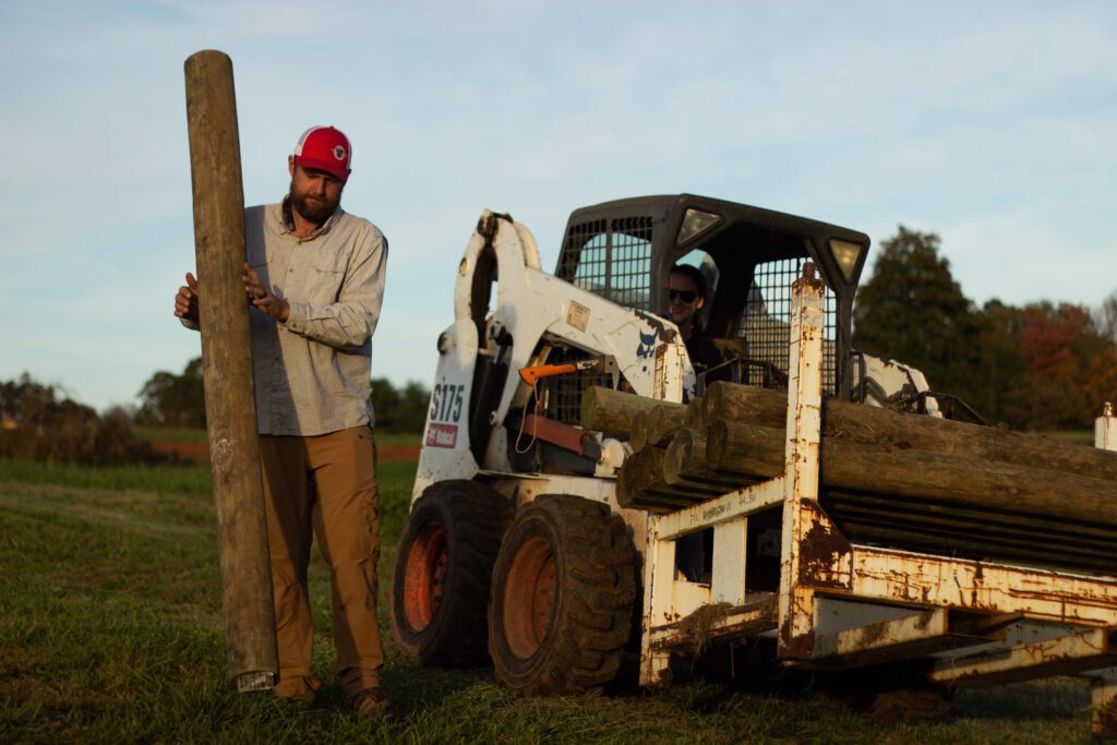Ryan pulls out a fence log and begins the process of building a new fence along his property on November 8, 2020, in Mt. Ulla, North Carolina.