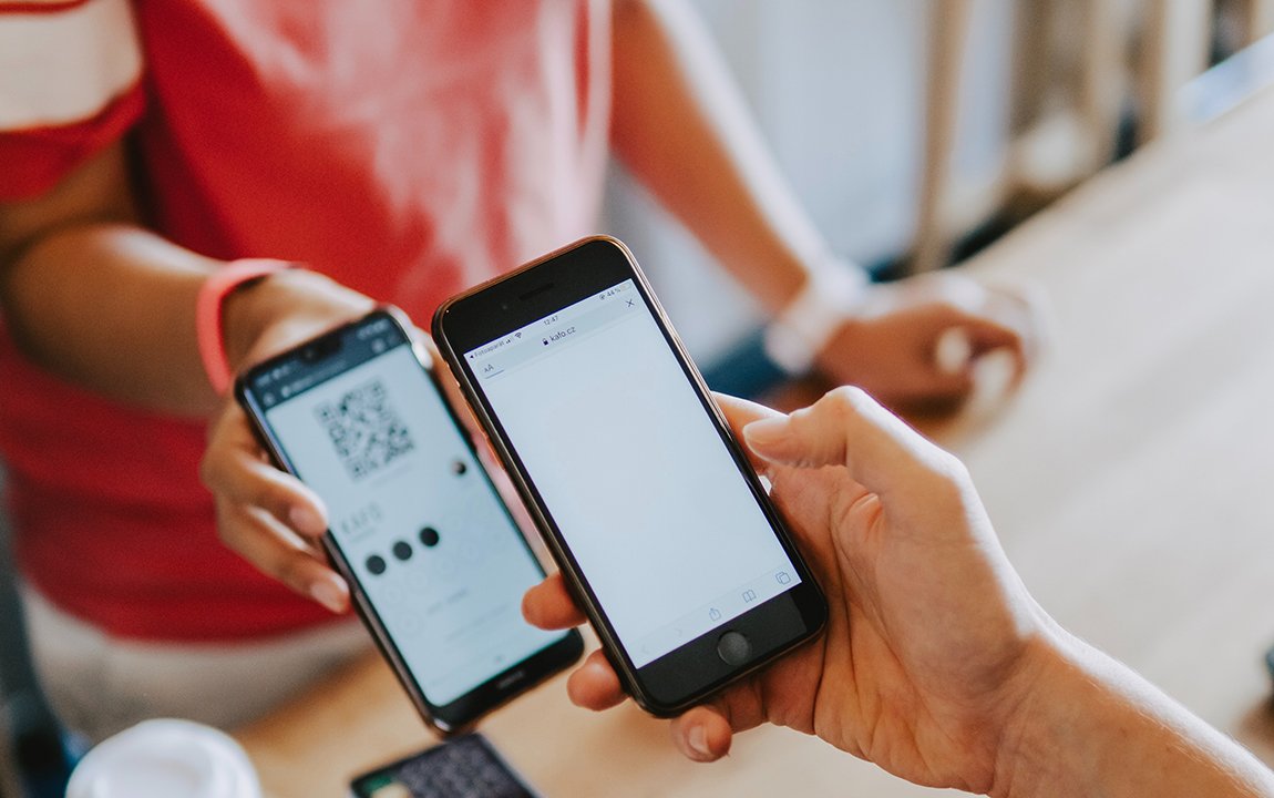 Two people using their smartphones, one displaying a QR code.
