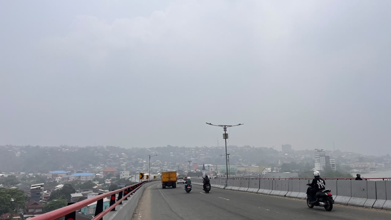 Verkeer op de Merah Putih-brug in Ambon, de heuvels verdwijnen in de rook