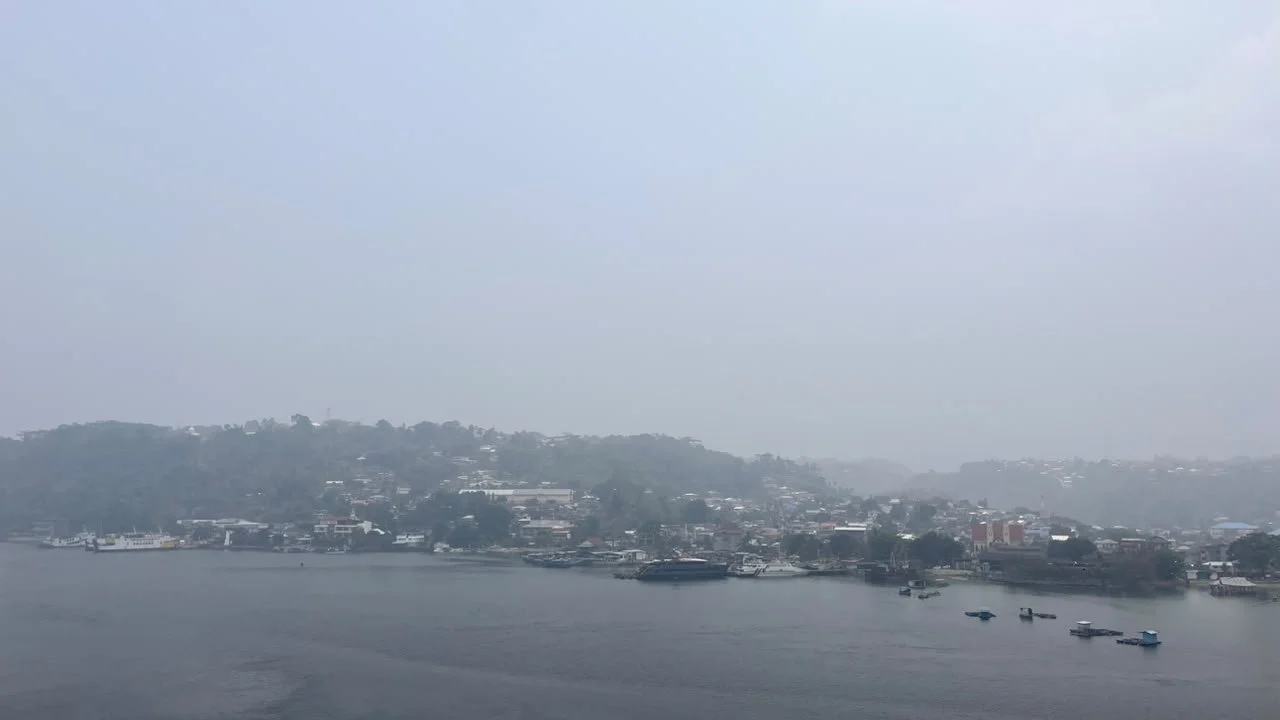 De baai van Ambon onder een grijze rooklaag