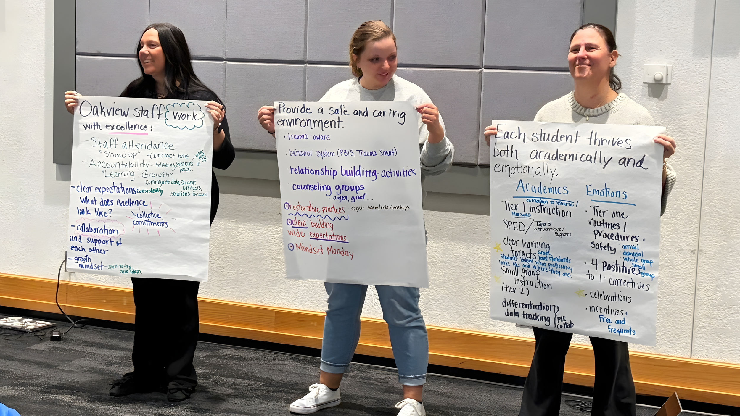 Three principals holding their chart paper with ideas to create a new mission statement