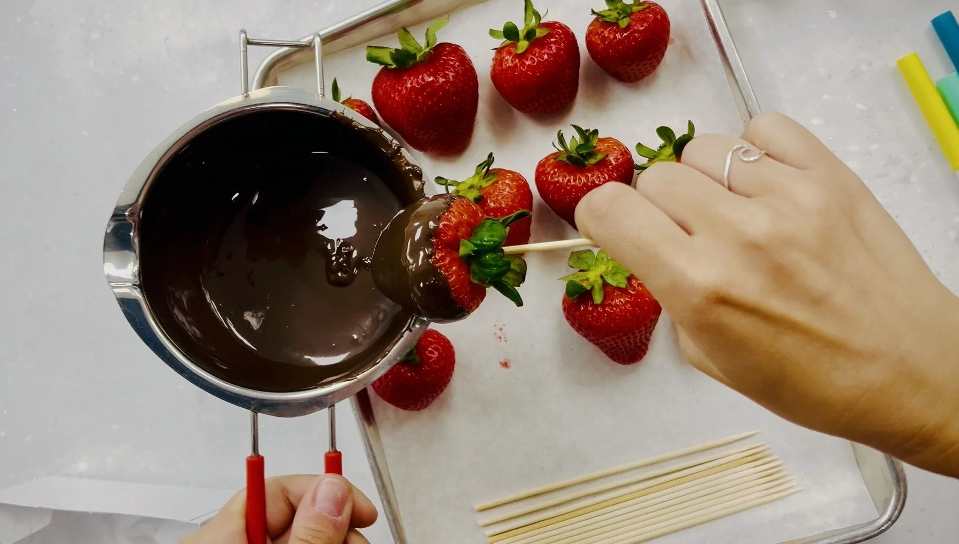 Chocolate covered strawberries being dipped during a DIY dessert decorating workshop at Dipped Haus