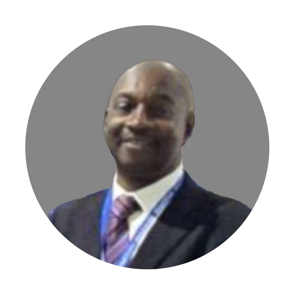 Portrait of a smiling man in a suit and tie, with a blue lanyard, against a gray background.