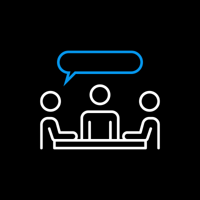 Outline of three people sitting at a table, with one person speaking and two listening, depicted with speech bubble above the speaker.