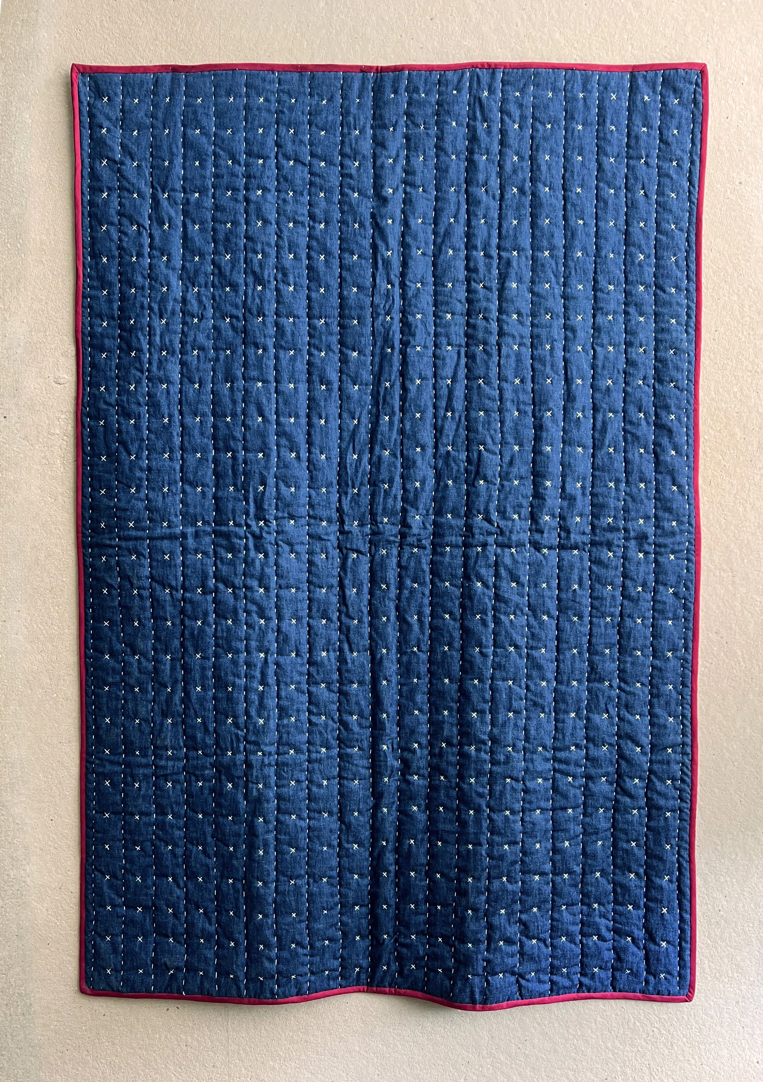 Outside of the blanket is hand embroidered with running stitches and X stitches on washed blue denim