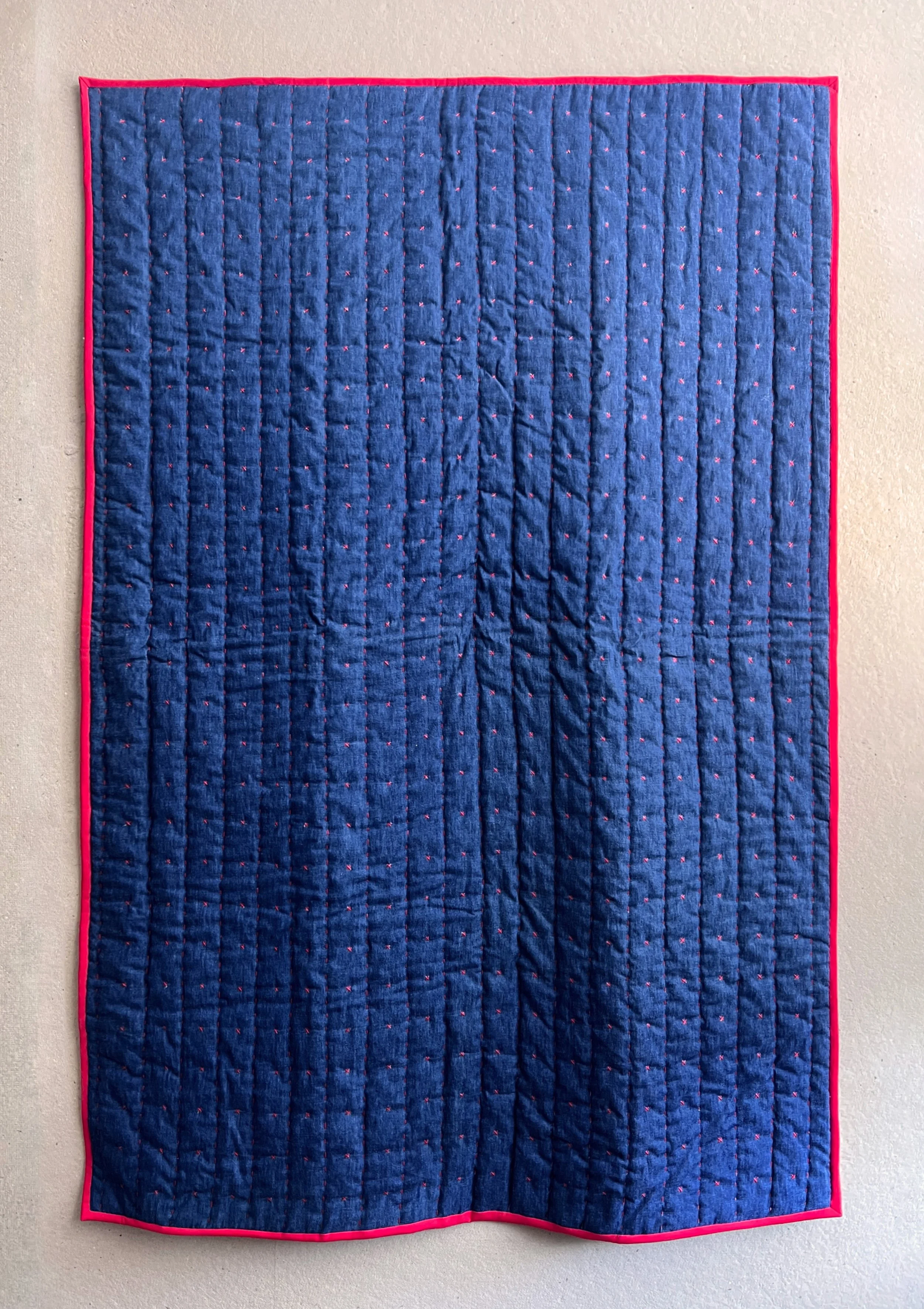 Outside of the blanket is hand embroidered with running stitches and X stitches on washed blue denim