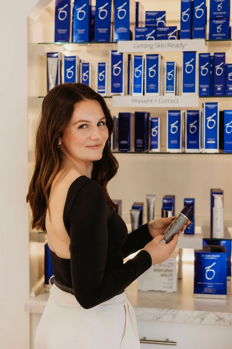 Registered Nurse Medical Aesthetics nurse injector wearing black shirt and looking at ZO product line