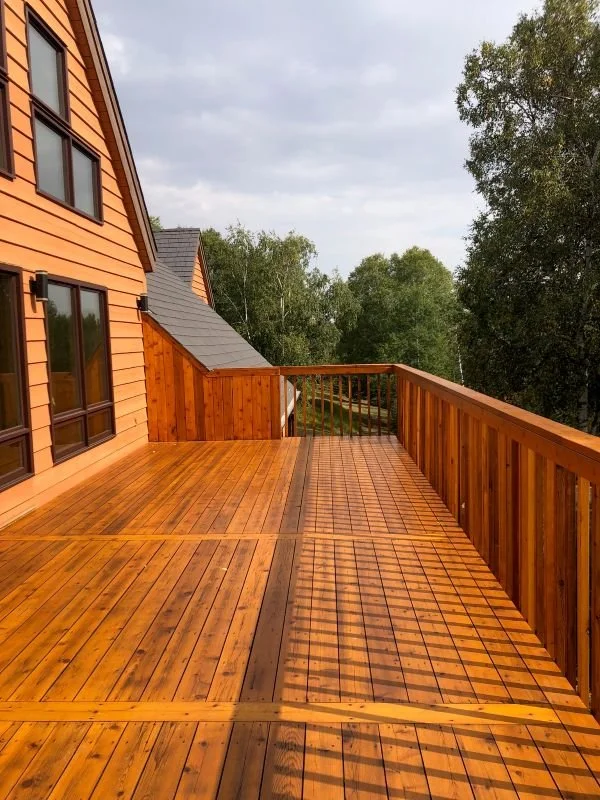 freshly stained cedar deck with home attached to left and situated on large country lot