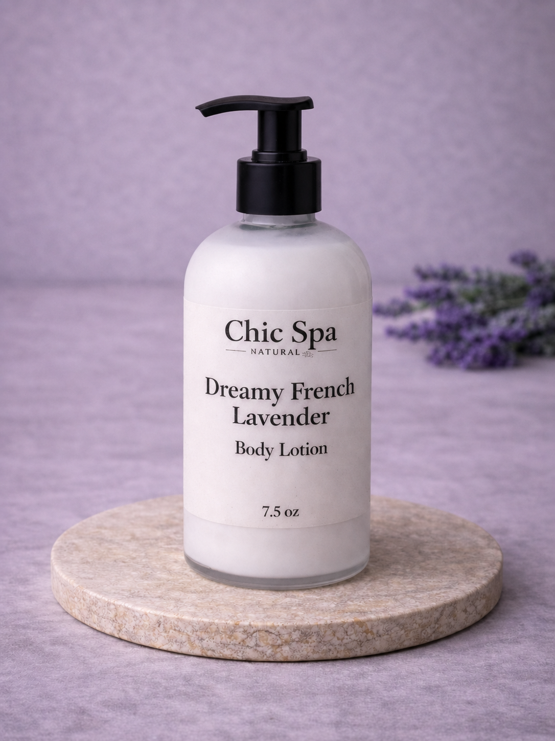 Chic Spa Naturals Dreamy French Lavender Body Lotion in a frosted glass bottle with black pump on a stone display with lavender background accents.