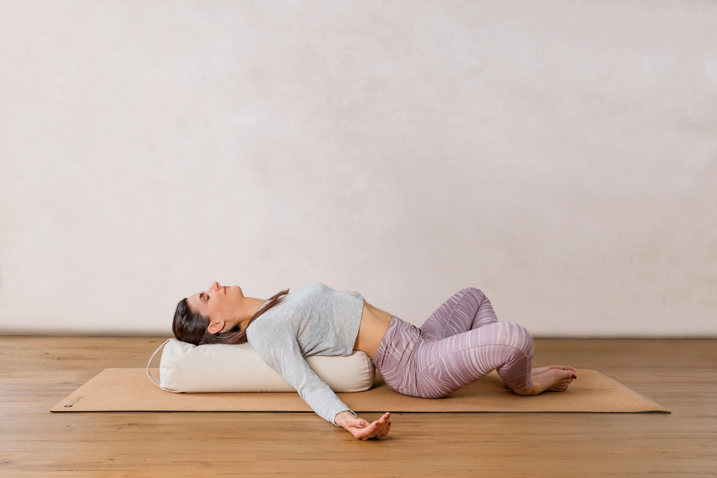 Person liegt entspannt mit geschlossenen Augen, während eine andere Person ihre Hände über den Kopf hebt.