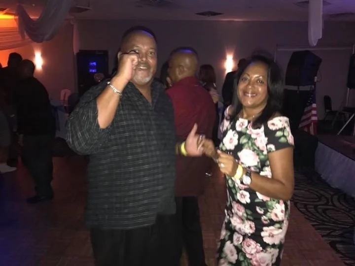 A man and woman dancing together at a social event with other people in the background.