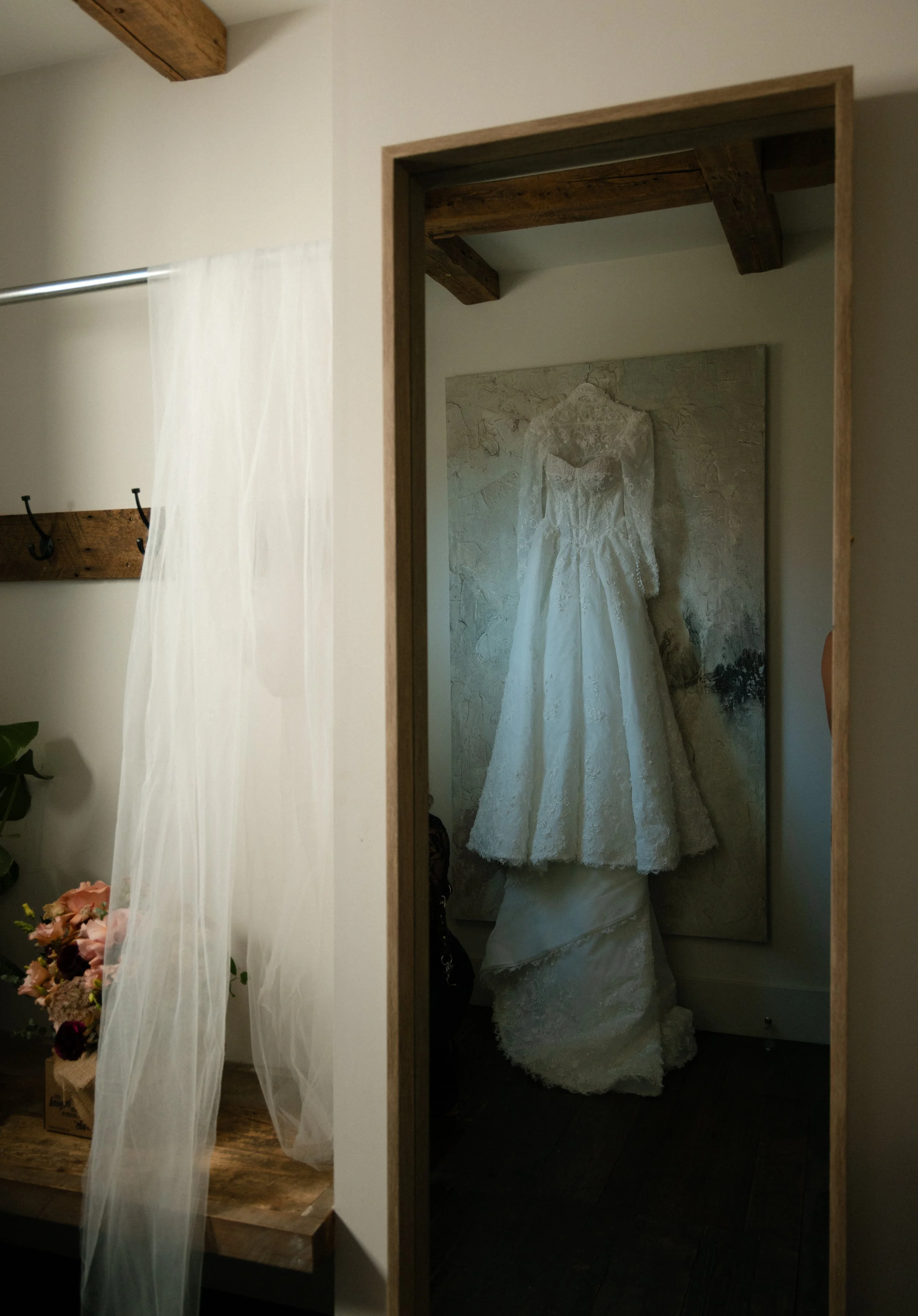Wedding dress hanging on a wall behind a mirror in a dressing room.
