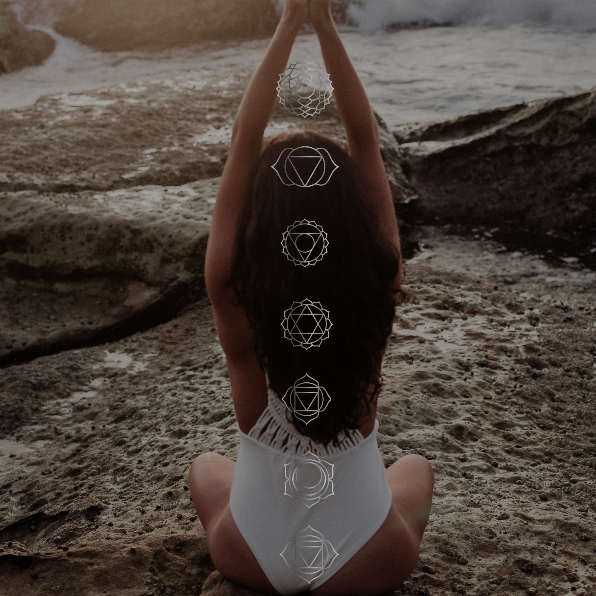 Person sitting on rocky beach in yoga pose with chakra symbols superimposed along spine.