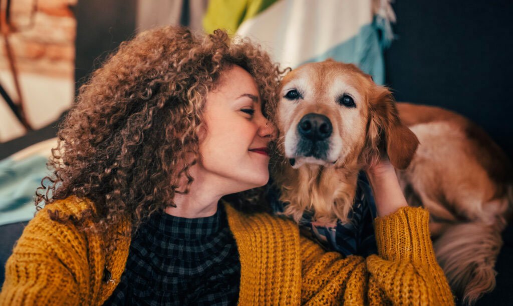 A woman gently cuddling her sick dog, sharing a quiet, tender moment of love and compassion, symbolizing the emotional bond during end-of-life care for pets.