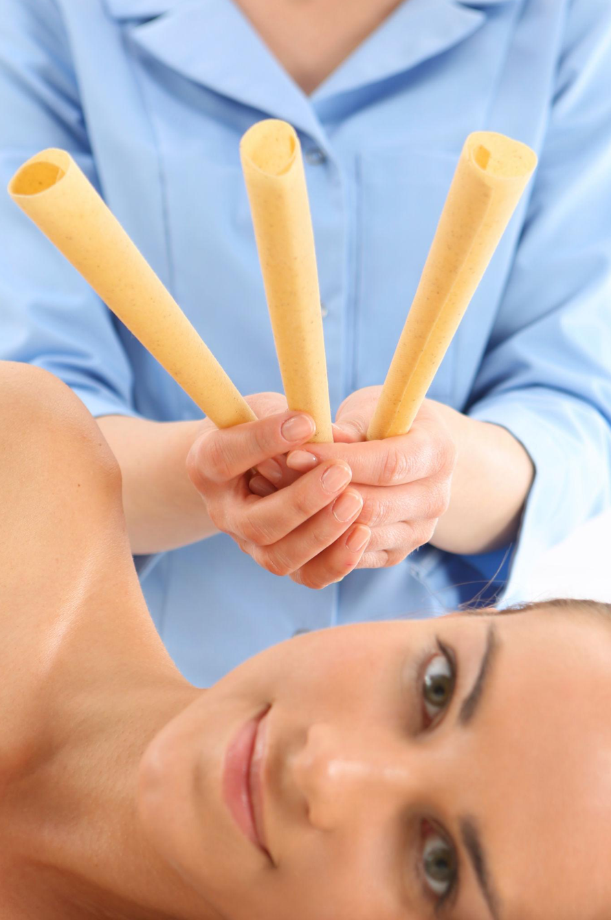 A woman lying down and smiling while holding four empty ice cream cones or wafer rolls in front of her.