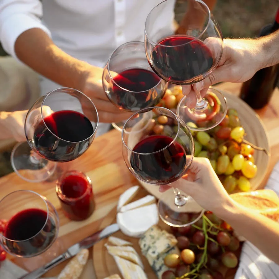 Four people clinking glasses of red wine