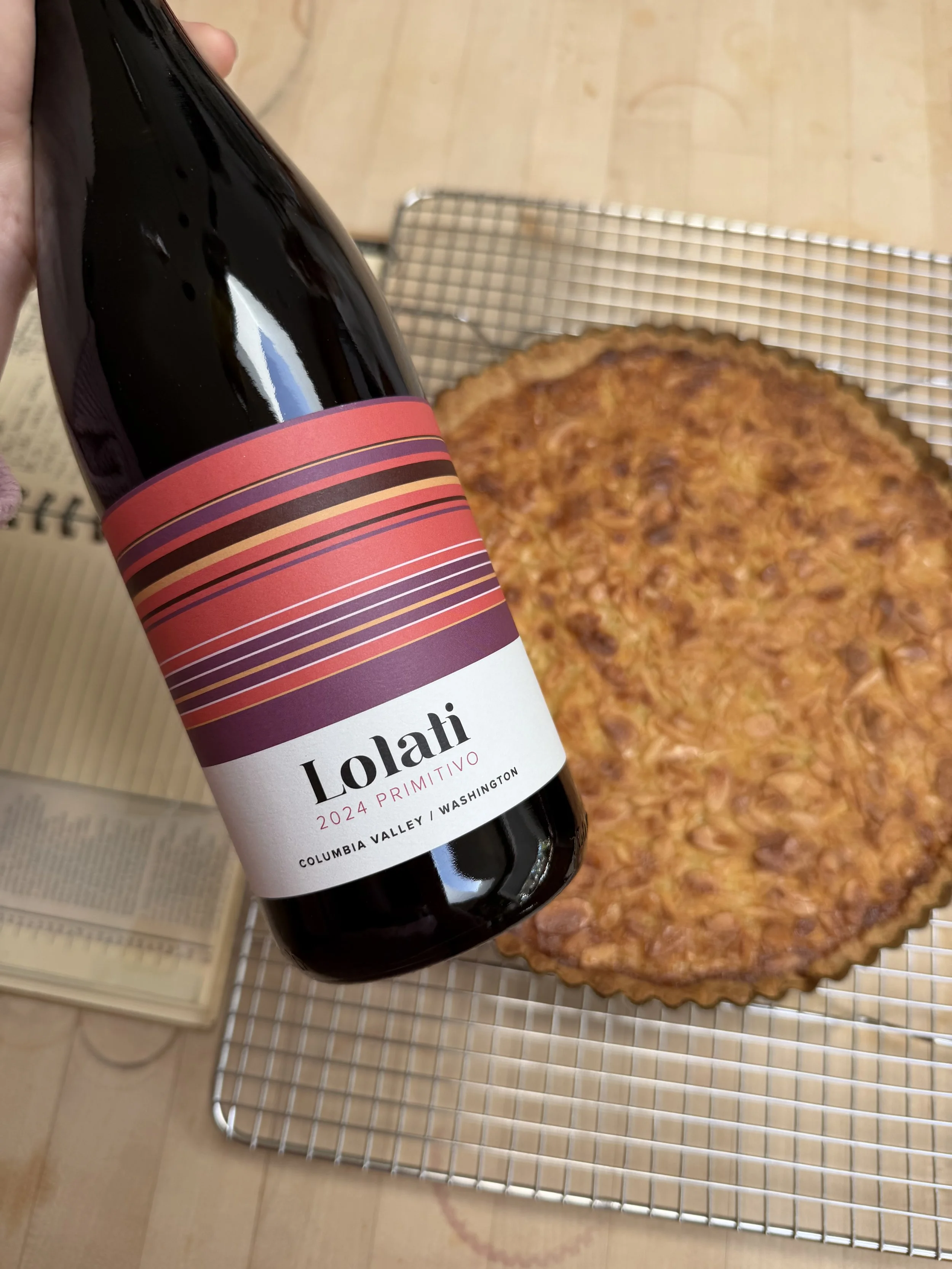 Bottle of Lolati Primitivo with an almond tart dessert in the background.