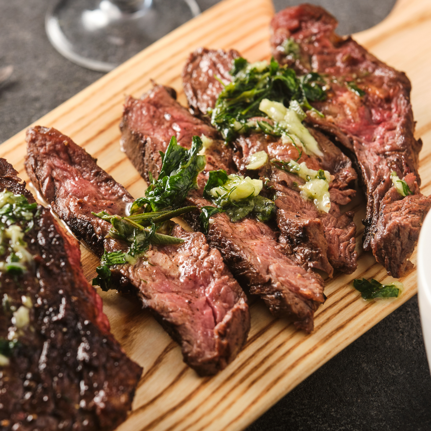 Cooked, sliced steak with garlic and herbs drizzled on top.