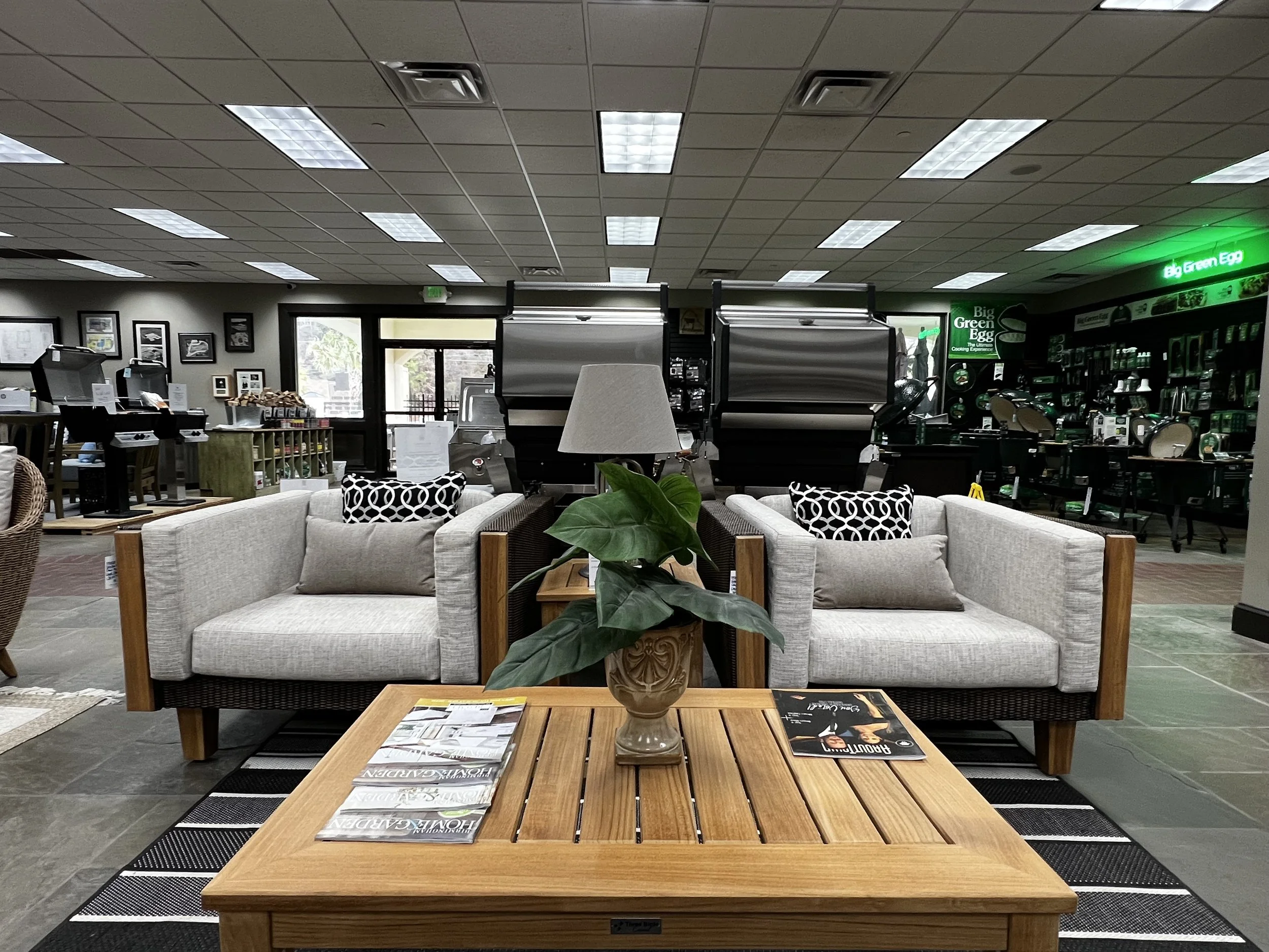Two oversized, light grey outdoor chairs and a wooden coffee table in Hollywood Outdoor Living's store